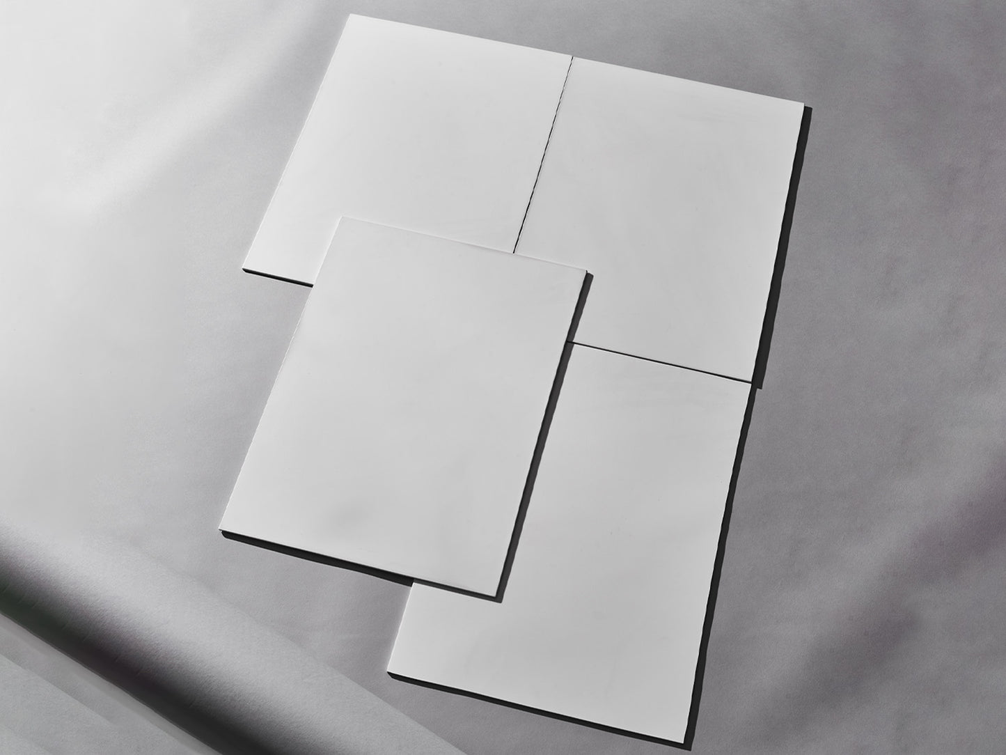 Vier weiße Fliesen auf grauem Hintergrund arrangiert.

Four white tiles arranged on grey background.